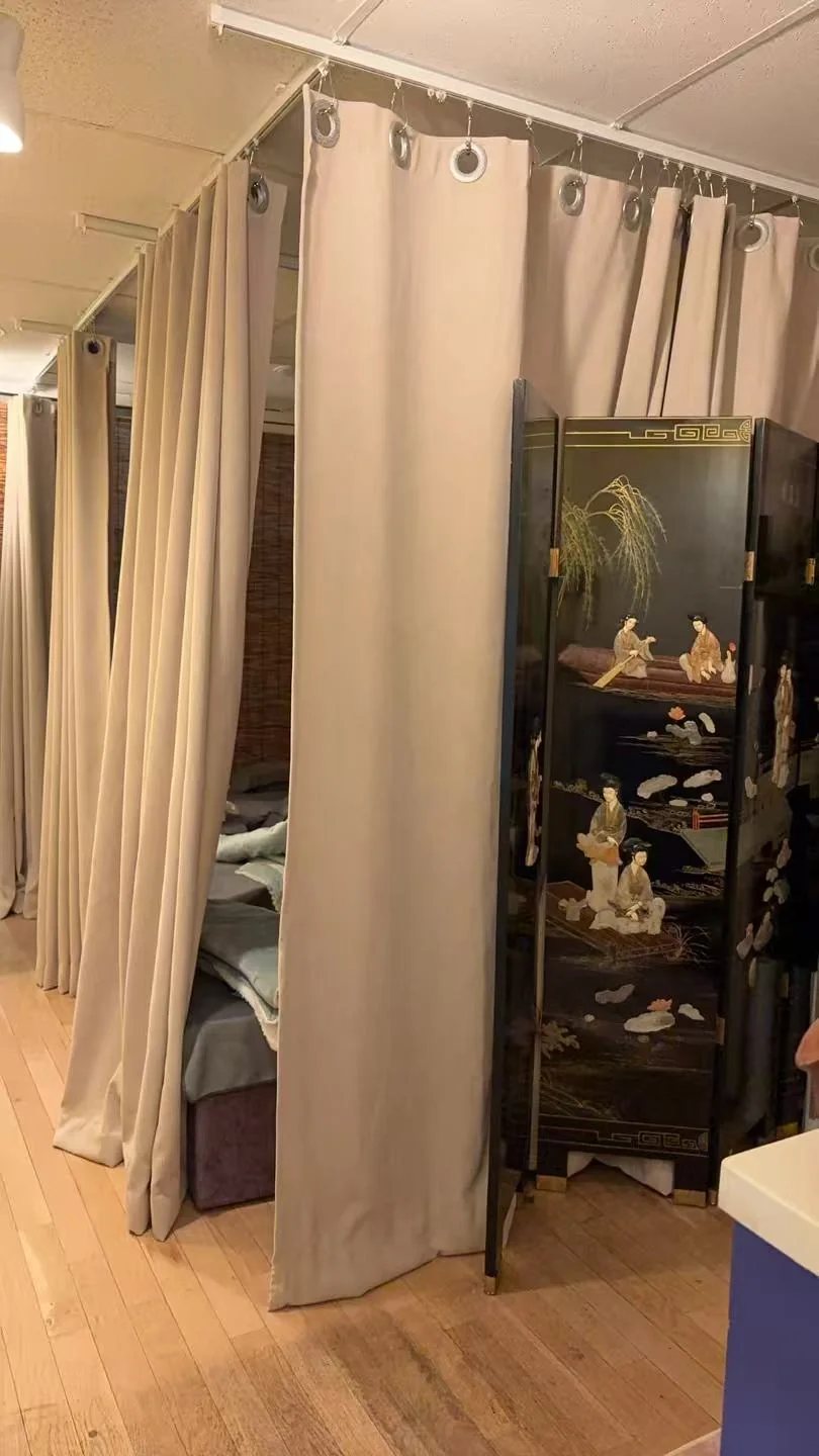 Row of curtained massage cubicles on a wood floor at U Beauty & Foot Spa, screened by a black lacquered Chinese folding panel